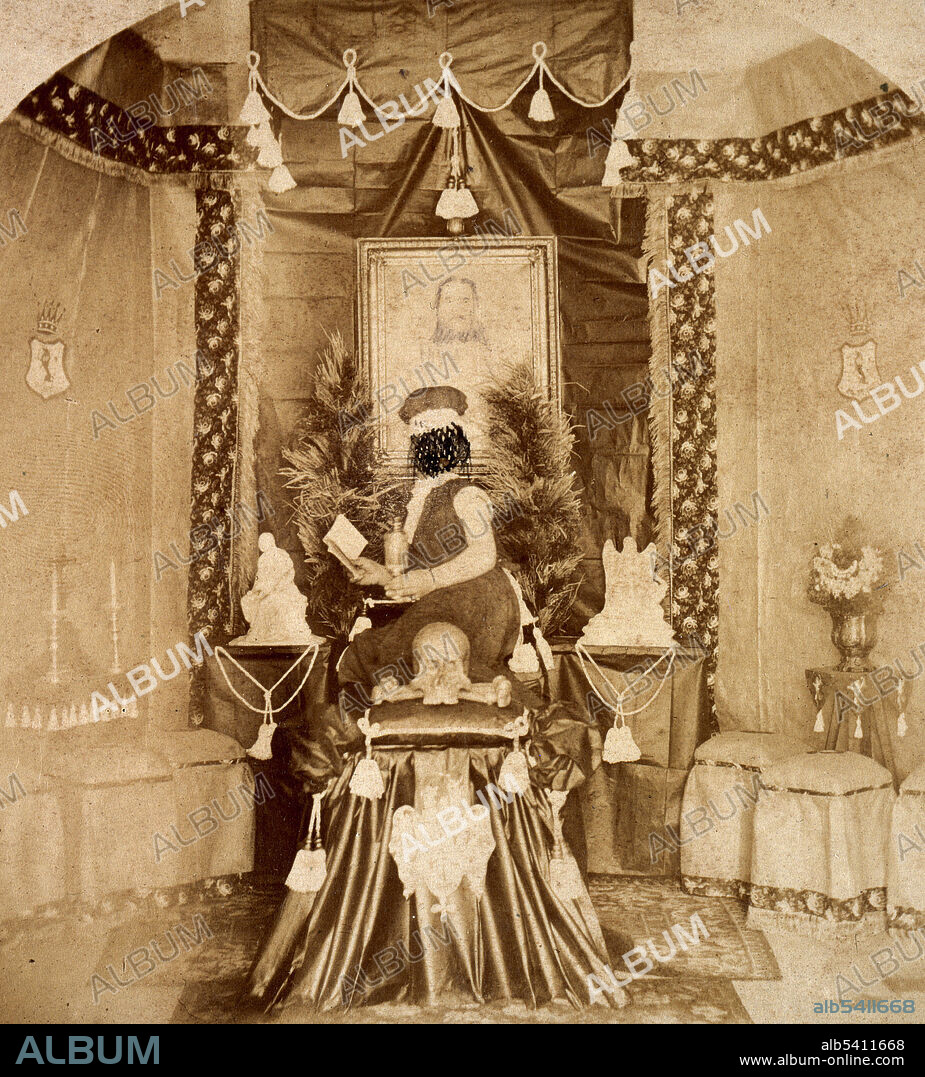 Person seated (on a covered coffin?) next to skull and cross bones, reading a book. The face has been crossed through with black ink. From the collection of Richard Freiherr von Krafft-Ebing (August 14, 1840 - December 22, 1902; full name Richard Fridolin Joseph Freiherr Krafft von Festenberg auf Frohnberg, genannt von Ebing) an Austro-German psychiatrist. He studied medicine at the University of Heidelberg, where he specialized in psychiatry. He later practiced in psychiatric asylums. After leaving his work in asylums, he pursued a career in psychiatry, forensics, and hypnosis. His principal work is Psychopathia Sexualis: eine Klinisch-Forensische Studie (Sexual Psychopathy: A Clinical-Forensic Study), which was first published in 1886 and expanded in subsequent editions. Psychopathia Sexualis is a forensic reference book for psychiatrists, physicians, and judges. Written in an academic style, its introduction noted that, to discourage lay readers, the author had deliberately chosen a scientific term for the title of the book and that he had written parts of it in Latin for the same purpose. Psychopathia Sexualis was one of the first books about sexual practices that studied homosexuality/bisexuality, and popularized the terms sadism and masochism. He considered procreation the purpose of sexual desire and that any form of recreational sex was a perversion of the sex drive. He died in 1902 at the age of 62. No photographer credited, 1890s.