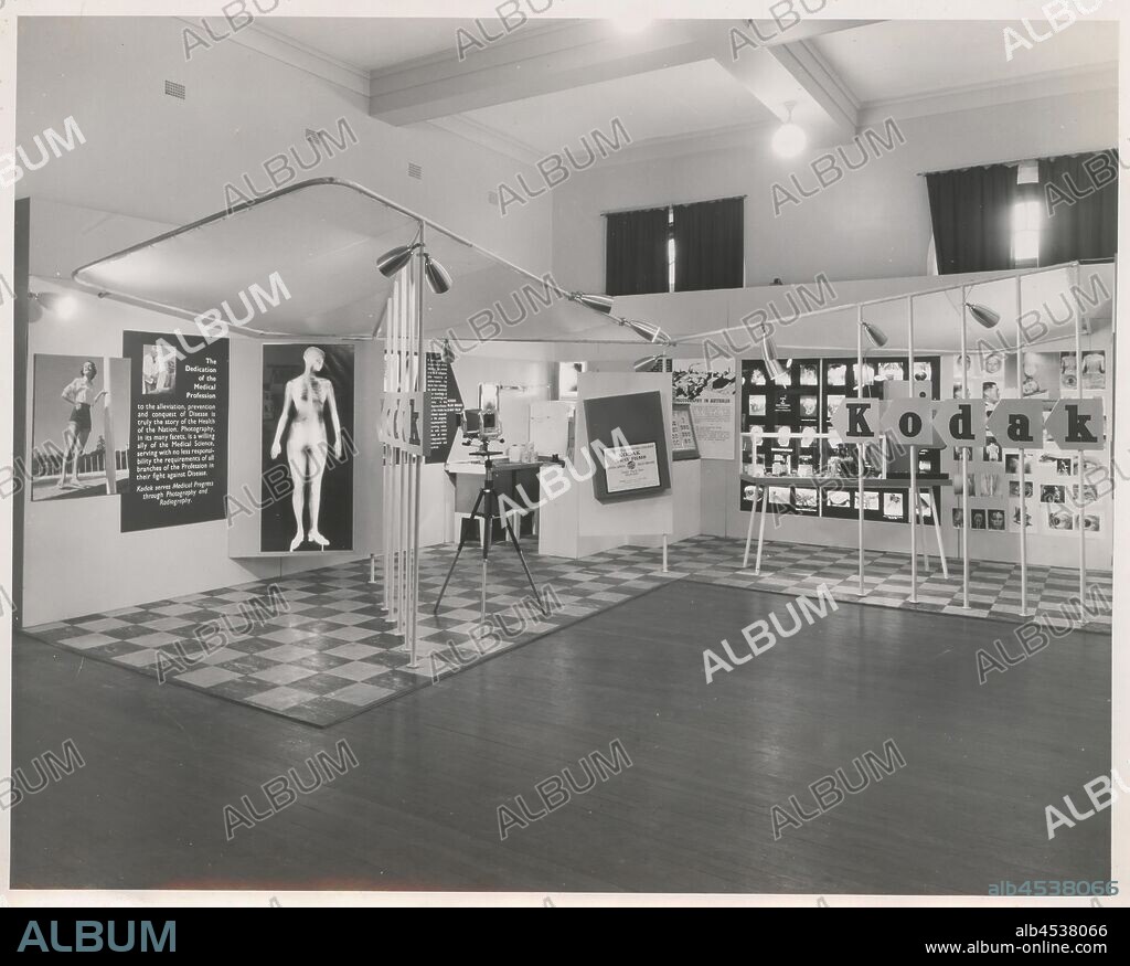 Photograph, Exhibition Stand, Medical Imaging, Sydney, circa 1940s, Black and white photograph of a Kodak Australasia Pty Ltd exhibition display stand themed around medical imaging (radiography and x-ray film). The L-shaped display features a chequerboard floor with angled display panels, posters and plinths. There is a large text panel to the far left accompanying a photograph of a woman in shorts and an x-ray image of a woman's body. The text panel is titled,.