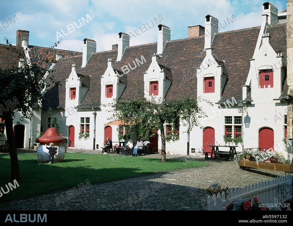 Gand (Belgique), Béguinage (fondé en 1240, la plupart des maisons du 17e/18e siècle ; Lange Viottastraat 71). Vue partielle : façades des maisons derrière la cour plantée de verdure.