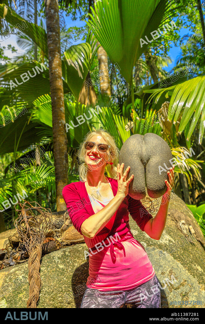 Tourist holding Coco de Mer at Fond Ferdinand Nature Reserve, near Anse Marie-Louise, Praslin, Seychelles, Indian Ocean, Africa.