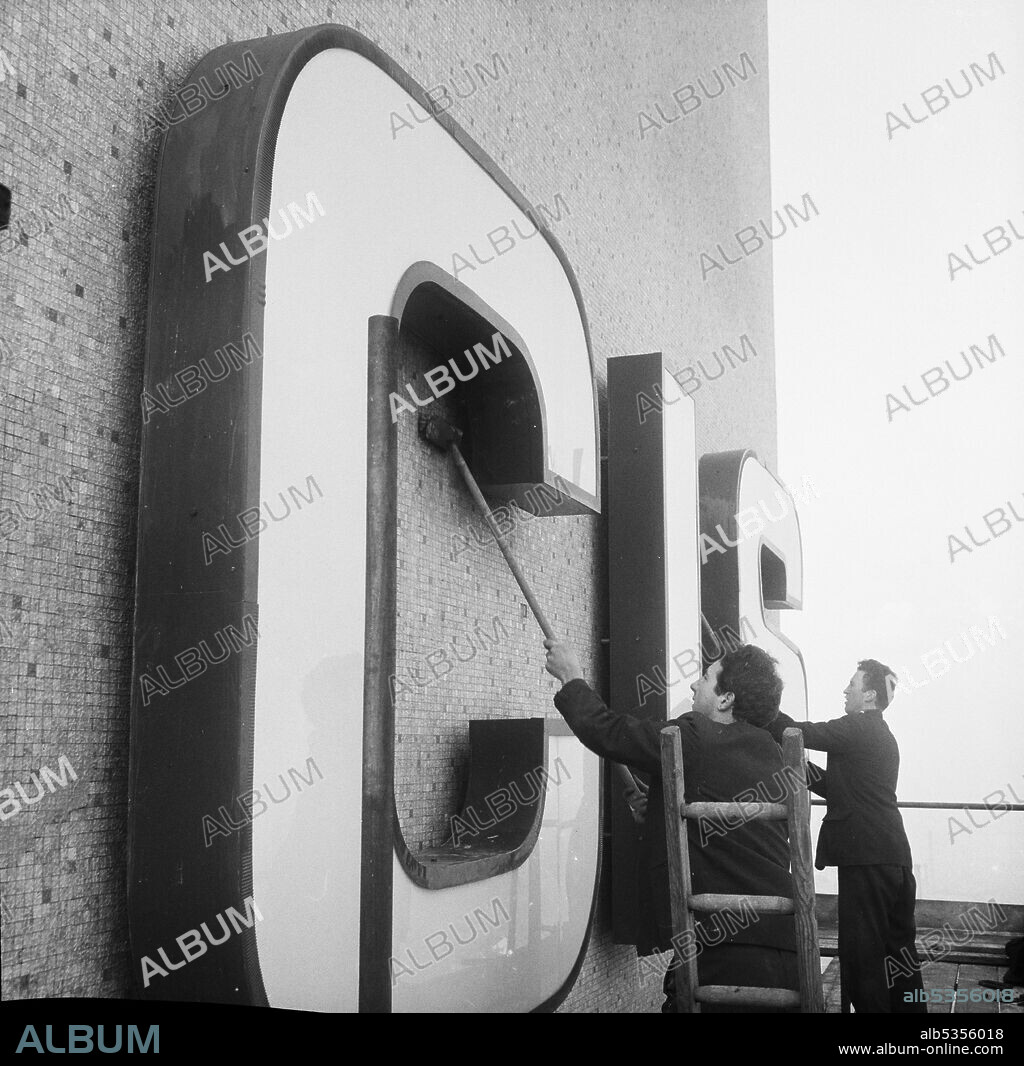 JOHN LAING PLC. Two Laing workers brushing mosaic tiling around 'CIS' lettering on the service tower of the Co-operative Insurance Society Building in Manchester. This image was catalogued as part of the Breaking New Ground Project in partnership with the John Laing Charitable Trust in 2019-20.