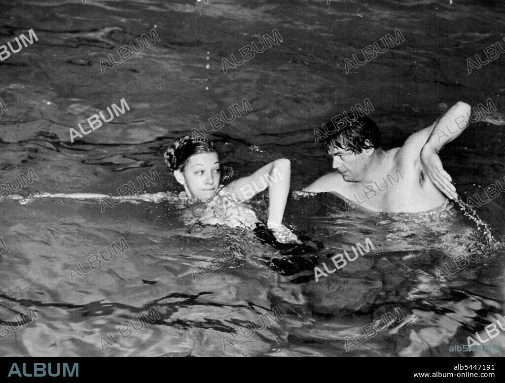Tarzan 'At Home'. Johnny Weismuller, 'Tarzan' of the film series, practices with his partner - British girl skater and swimmer, Belita Jaepson Turner, at a London baths for the Health and Holiday Show in which they will appear at Earl's Court, London, at the and of the month. February 16, 1948.