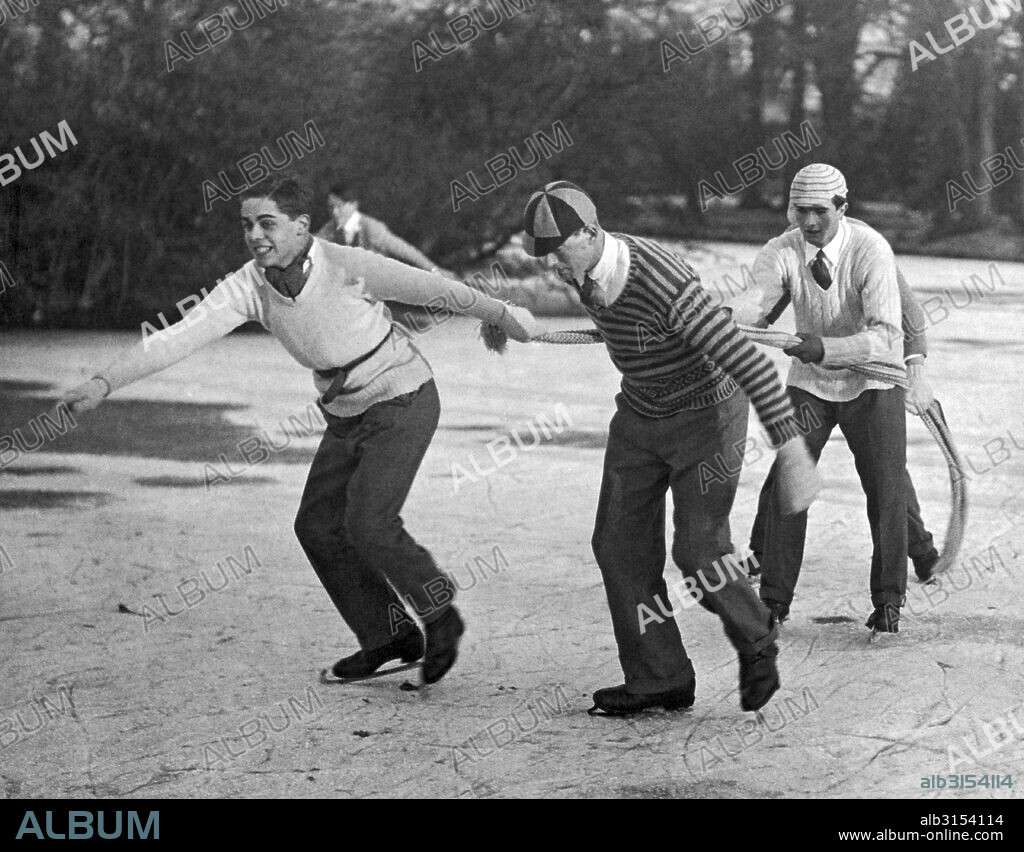 Eton, England:  1925. Eton College celebrated its 485th birthday by giving the boys a holiday, which most spent skating on the lake at Ditton Park. These boys are using a scarf as a tow rope.