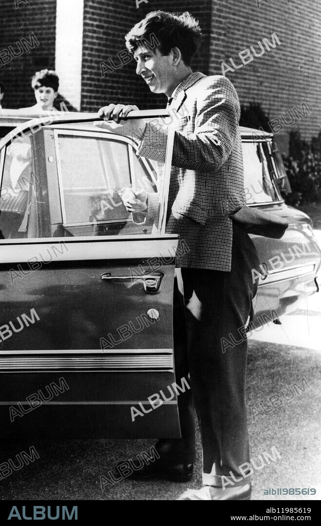 PRINCE CHARLES VISITS GEELONG GRAMMAR SCHOOL. 7 March 1966. Prince Charles paid his first visit to Geelong Grammar School, Geelong, Victoria, Australia, recently. In a 22 and a half minute official tour of the school, just outside Geelong, rosy cheeked Prince succeeded in 1) causing three staff members, the bus driver, the porter and the cook, to remark about his humour and inquisitiveness 2) Showing himself up as a typical schoolboy by not having a pen at a critical time and 3) proving to four fit prefects that he was no slowcoach when is came to scaling the schools clock tower. But the Princes first day at Geelong was strangely quiet, the classrooms were empty and eager sightseers were scarce. It happened to be sports afternoon and all the students were out either boating or rowing on the adjoining lagoon, playing in house cricket matches, or training for swimming sports. Photo Shows: One last smile for photographers as Prince charles leaves after his visit to Geelong Grammar School.