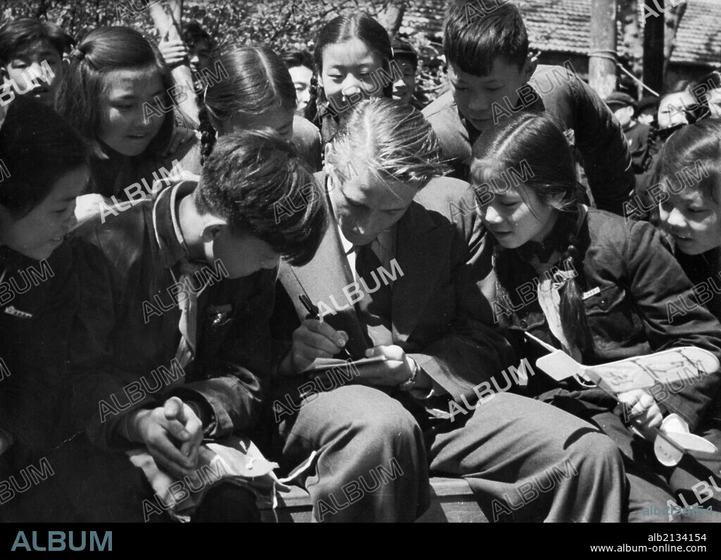 Korean War. April 1955. Ex-soldier of the Belgian battalion of the 'US Command' in Korea, Roger F. Hoste, crossed the Military Demarcation Line in Korea to the Korean-Chinese side on August 25. He refused repatriation to the American side at the secretaries' meeting on February 11th. The Red Cross Society of China assisted him to come to China and helped him get his job at the Shantung Paper Mill in Tsinan, Shantung Province. Here, students of Tsinan, who are visiting the mill during their spring holiday, are asking Hoste for his autograph. (Photo by: Sovfoto/UIG via Getty Images).
