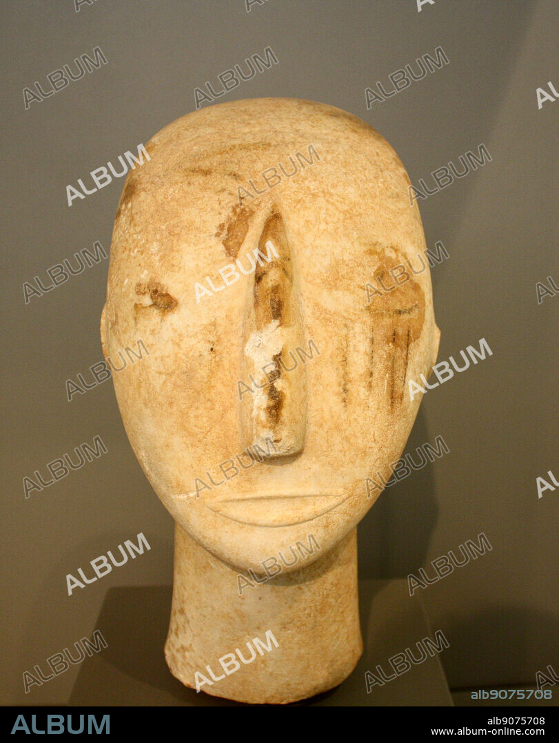 Head of a Cycladic statue. Sculptured nose, mouth and ears. Painted eyes and red vertical striations on the right cheek. Parian marble; found on Amorgos. Early Cycladic II period (Keros-Syros culture) 2800-2300 BC.
