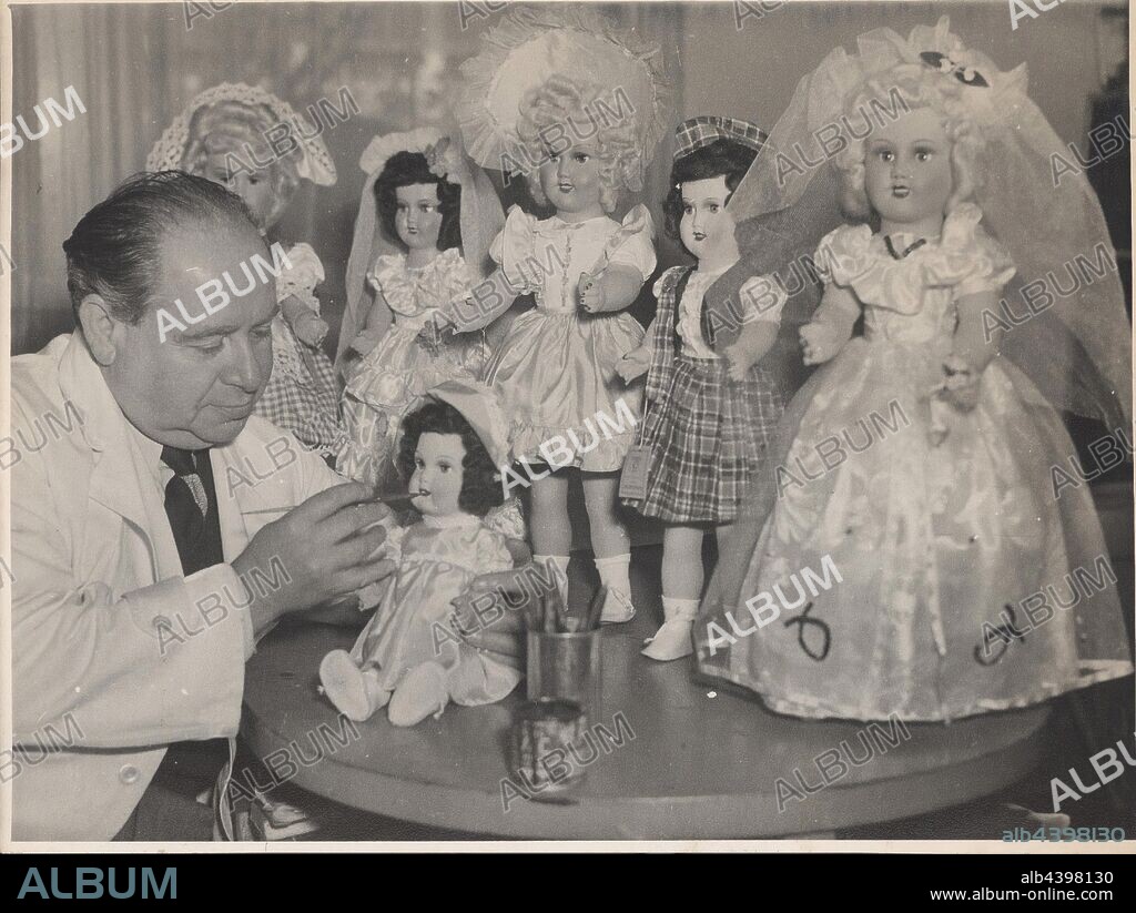 Photograph - L. J. Sterne Doll Co., Leo Sterne Painting Lips on Doll, Melbourne, Oct 1953, Black and white photograph of Leo Sterne painting lips on one doll with a further five dolls manufactured by the L. J. Sterne Doll Company in the background. This photograph relates to products and promotions of the L.J. Sterne Doll Company (1939-1971), a Melbourne doll and toy manufacturer founded by Austrian migrants Leo and Hilda Sterne.
