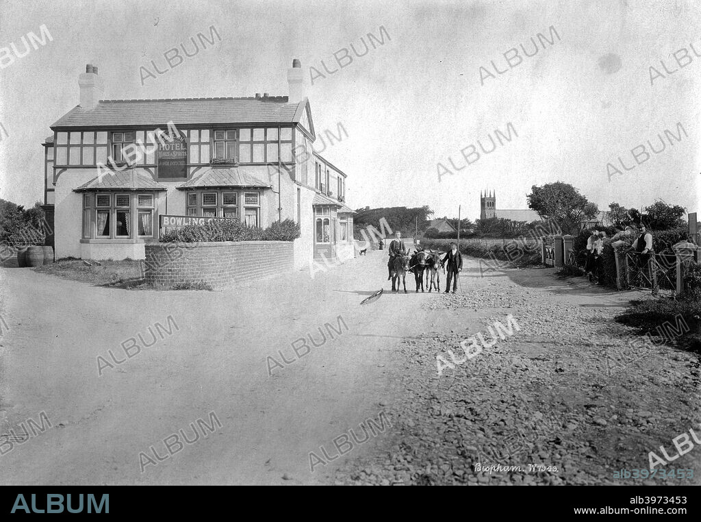 Red Lion Hotel, Bispham, Lancashire, 1890-1910. The Red Lion Hotel in Bispham with the church of All Hallows in the distance. Two men lead three donkeys up the road towards the camera.