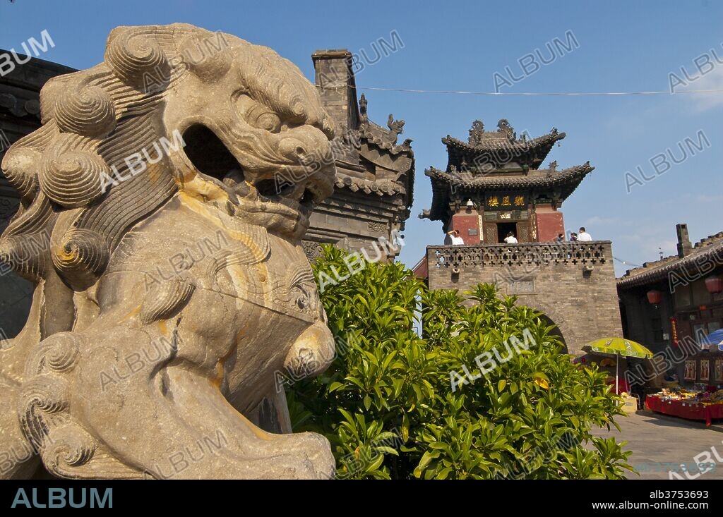 Stone lion in front of a gate in Pingyao, renowned for its well-preserved ancient city wall, UNESCO World Heritage Site, Shanxi, China, Asia.