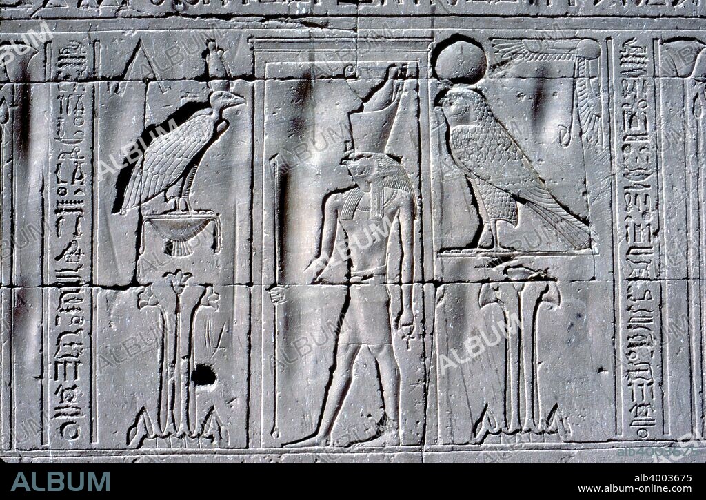 Relief of Horus (falcon-headed god), Temple of Horus, Edfu, Egypt, Ptolemaic Period, c251 BC-c246 BC. Horus (falcon-headed god) wearing the Double Crown of Upper & Lower Egypt and holding the Sceptre & Ankh stands between the Vulture of Upper Egypt wearing the White Crown above a lotus plant and the hawk of Lower Egypt above papyrus reeds.
