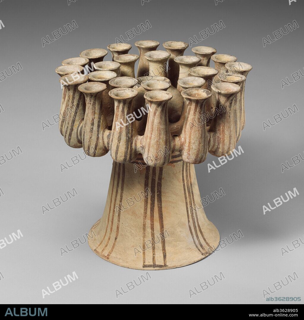 Terracotta kernos (vase for multiple offerings). Culture: Cycladic. Dimensions: Overall: 13 5/8 in. (34.6 cm)
Other: 14in. (35.5cm). Date: ca. 2300-2200 B.C..
Although the kernos was used in widely disparate regions during the prehistoric period, particularly impressive examples have come to light in the Cyclades, and this is one of the grandest preserved.  The receptacles probably contained foodstuffs of various kinds or perhaps of flowers.
The kernos was found, together with the jar (2004.363.2) and the jug (2004.363.3) displayed nearby in this gallery, in 1829 in a tomb on Melos by Captain Copeland, a British naval officer.  In 1857 his widow gave the objects to Eton College, where they remained until coming to the Metropolitan Museum of Art on loan in 1996.