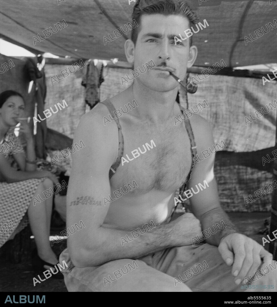 DOROTHEA LANGE. Unemployed lumber worker goes with his wife to the bean harvest. Note social security number tattooed on his arm. Oregon.