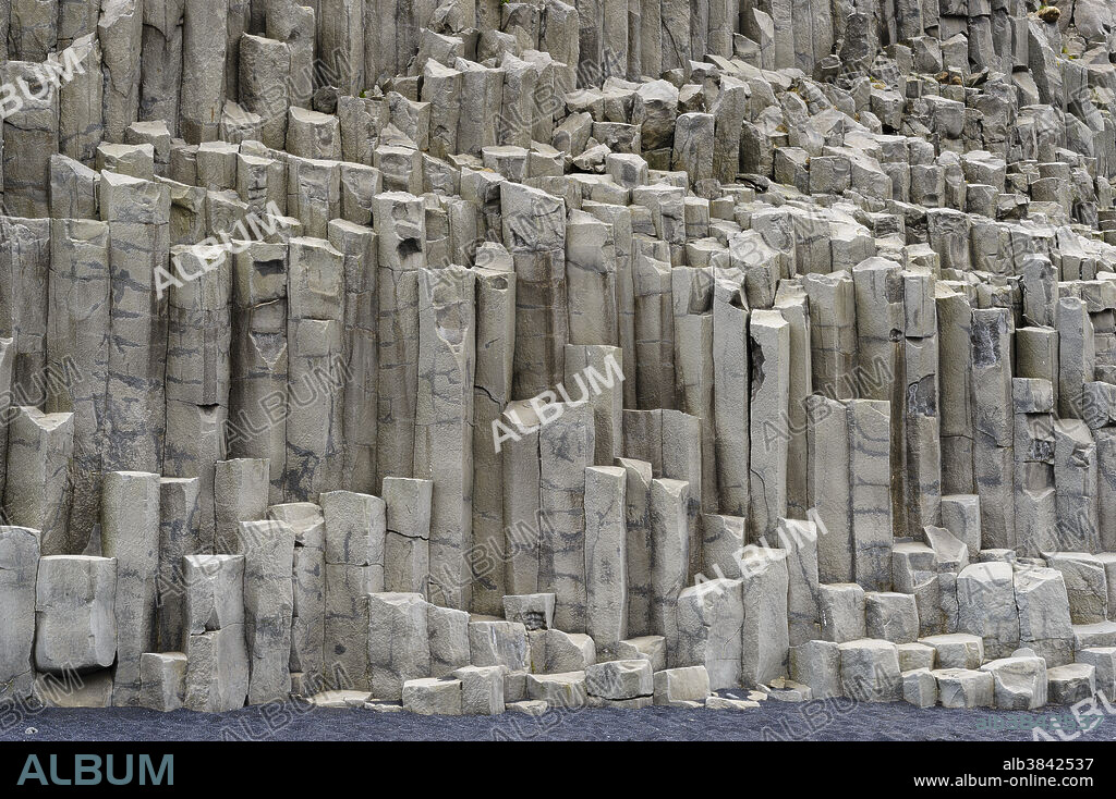 Basalt columns and the black beach at Reynisfjara; near Vik, Iceland. Basalt is an extrusive igneous rock, which means it forms from the cooling of lava on the surface. Contraction of the lava as it cools leads to the geometry of the columns, which have either hexagonal or pentagonal cross-sections. The black sand is formed by the erosion of the columns by the sea.