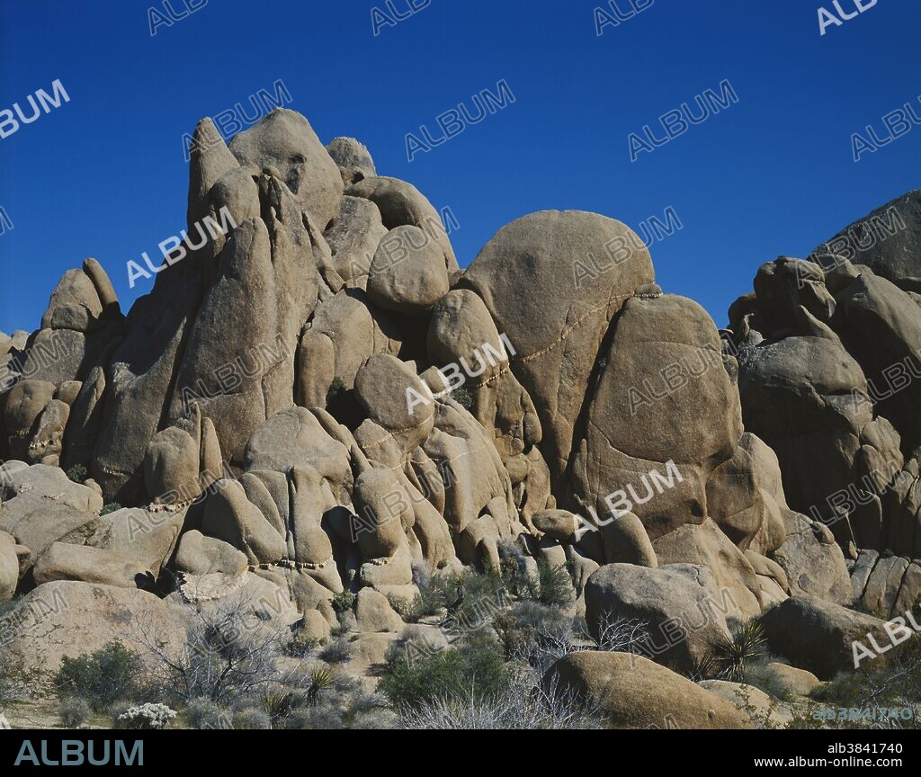 Vertical jointing breaking up an inselberg, with the boulders rounded by spheroidal weathering, in Joshua Tree National Park, California.  An aplite dike runs through the monzogranite.