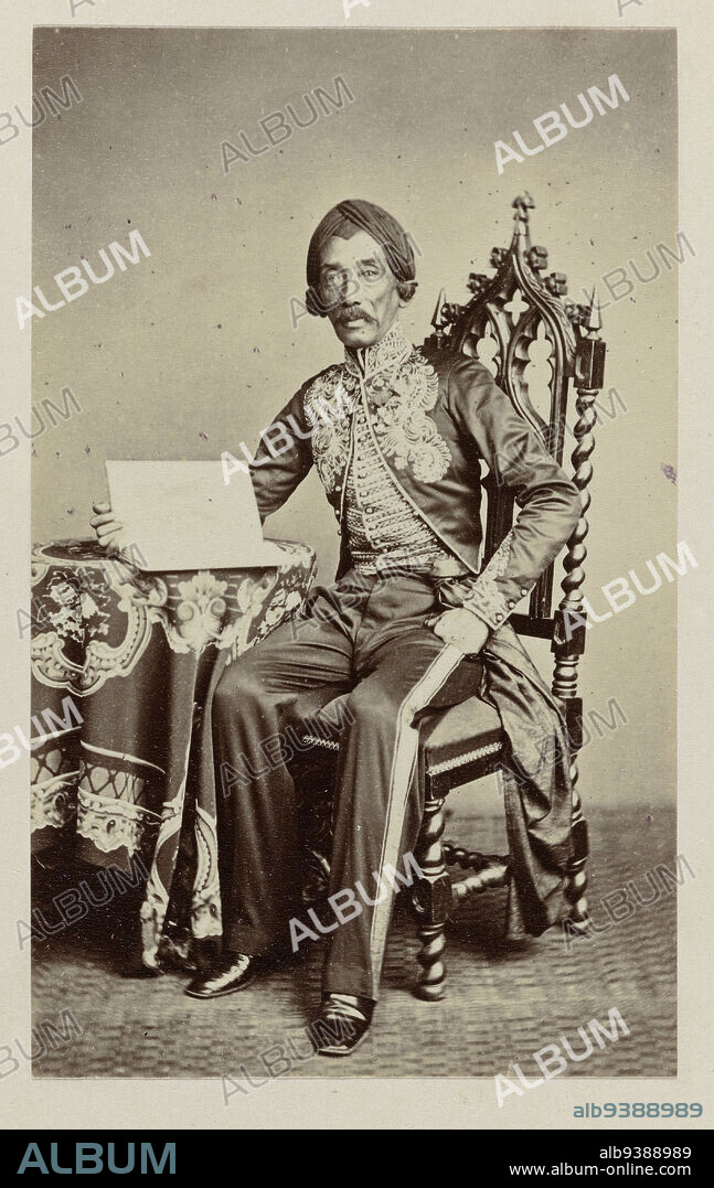 The painter Raden Saleh, Studio portrait of the Javanese painter Raden Sarief Bastaman Saleh, seated in a chair at a table on which lies a book. Pasted-in photograph in the photo album titled: Faces of Java., Woodbury & Page, Batavia, 1860 - in or before 1872, photographic support, albumen print, height 92 mm × width 57 mm.