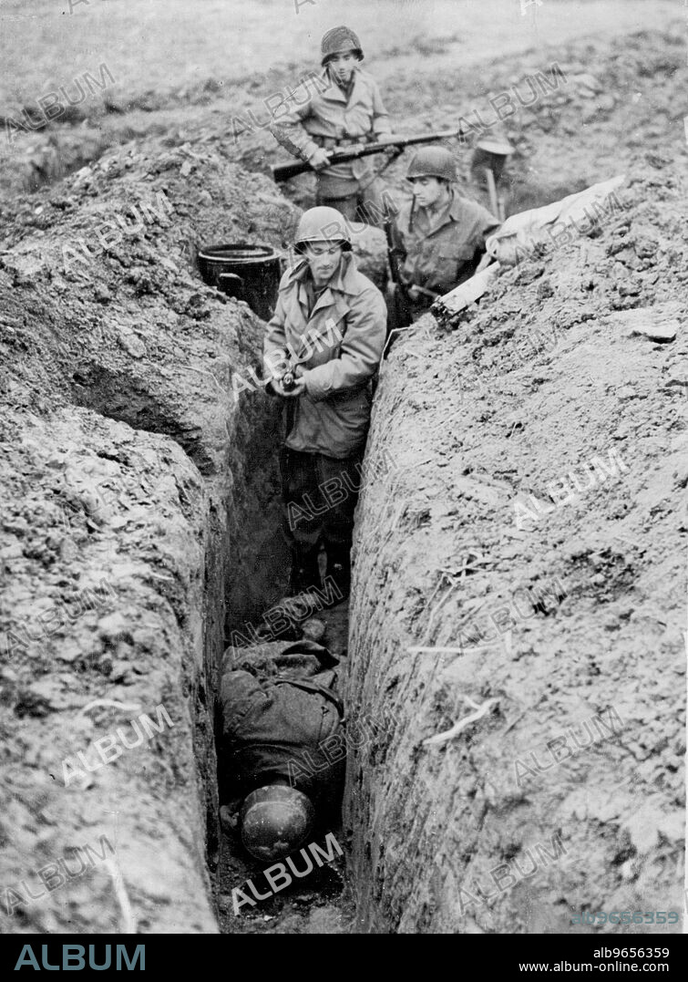 Ninth U.S. Army launches surprise Assault -- Infantrymen of the Ninth U.S. Army clear a captured slit trench where a dead Nazi soldiers lies face downward on Reich soil. Ninth Army forces, which were moved secretly across France, Belgium and Holland and placed on a front between Geilenkirchen and Eschweiler, Germany, captured five German towns in the first few hours of fighting after a new all-out offensive was launched November 16, 1944. by six allied armies closing in on the Reich. December 17, 1944. (Photo by Keystone Photo).