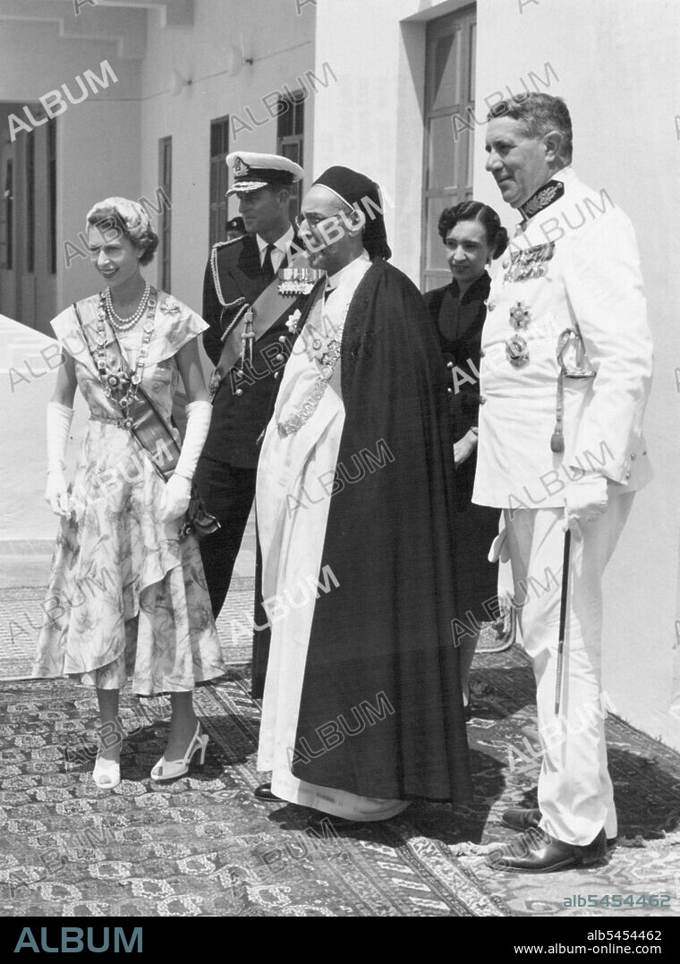 "The Queen Is Home" -- With King Idris of Libya, at his palace in Tobruk, Her Majesty the Queen and the Duke of Edinburgh appear on the balcony overlooking the harbour. Lying there at her mornings was the Royal yacht "Britannia" with Prince Charles and Princess Anne on board waiting for the happy reunion wish their parents after the long months of separation. June 1, 1954.