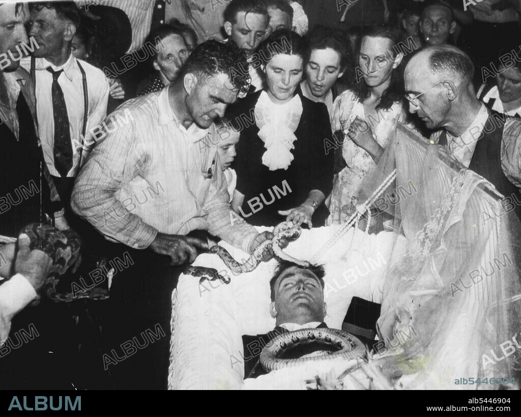 Weird Kites: During the funeral service of Lewis Ford at the Dolly Pond Church of God at Chattanooga, Tennessee, the rattlesnake which had caused his death during a religious ceremony was placed on his head by the Rev. Raymond Hayes. Ford's widow is at the head of casket, pats the snake. September 29, 1945.