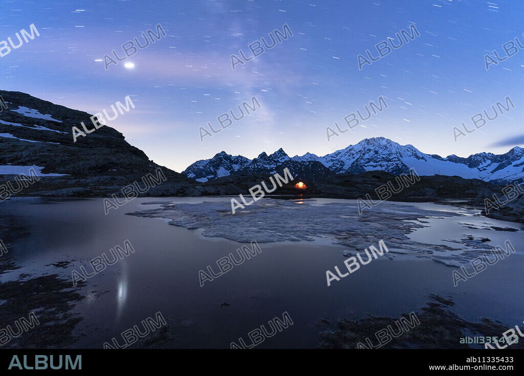 Tent under starry sky and Milky Way with Monte Disgrazia in background, Alpe Fora, Valmalenco, Sondrio province, Lombardy, Italy, Europe.
