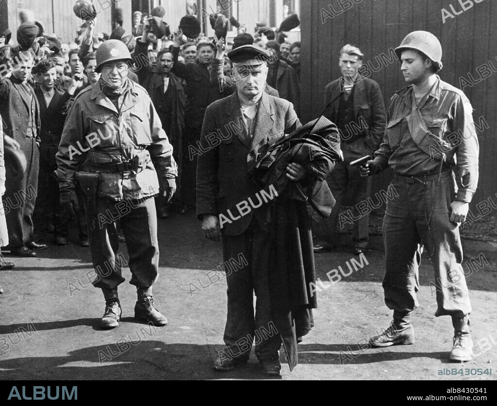 Orig. bildtext... LIBERATED PRISONERS CHEER AS NAZI IS TAKEN Altendorn, Germany. Happy liberated slave laborers wave and cheer as Major Anthony J. Malankowski, of Maspeth, Long Island, left, and PFC. Arthur Fields, lead away the Nazi Commandant of the slave labor camp here. The commandant was taken to U.S. First Army authorities to answer atrocities charges at his camp. Anm. Pistoler Fångar Tvångsarbetare CD69 sites: ALTENDORN ;TYSKLAND ;USA*.