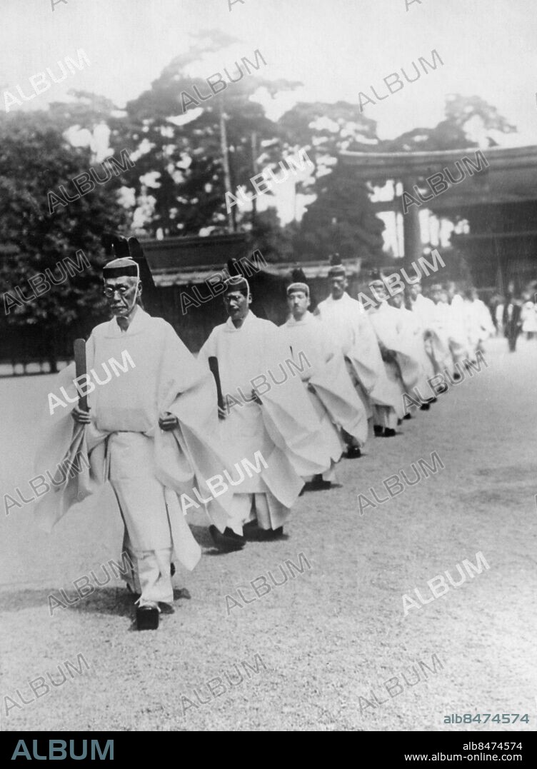RELIGOUS CEREMONY AT SHRINE OF JAPANESE EMPEROR. Sevices commemorating the 17th anniversary of the death of Emperor Meiji of Japan, were recently held at the Meiji Shrine in Tokyo. O.P.S. Ritualists in solemn procession at the Meiji Shrine in Tokyo, Japan. The procession is led by Chief Ritualist Hyoye Ichinche, one time Commander of the Imperial Guards Division, who gave up his Military career to devote the rest of his life to religous services to the memory of his former Emperor. Anm. Processioner Ceremonier Minnesceremonier Grusplan Tempel På rad Minneshögtider Kolonner Ritualister Ritualer Traditionell klädsel CD366 persons: HYCYE ICHINCHE sites: JAPAN.