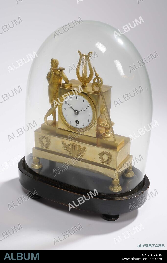mantel clock, Anonymous, approx. 1800, glass, wood, enamel, brass, Total: 36 x 26 x 15.8cm 360 x 260 x 158mm, Bell: 30.8 x 23.5 x 13.8cm 308 x 235 x 138mm, Base: 6 x 26 x 15.8cm 60 x 260 x 158mm, flute, music making, lyre, Empire fire-gilded brass mantel clock under glass bell jar. On the right side of the clock a boy playing a flute in a short tunic leans, on top of the clock a four-stringed lyre, on the left a long staff with two wreaths and a lion's head with a bowl underneath. The clock and figures are on a beam with three wreaths on the front, the middle of which contains a harp. The whole stands on four bell-shaped legs with a stripe pattern. The dial is enamelled in white with black numbers. The glass dome has an oval shape at the bottom and a round top. A piece is missing along the edge. The mantel clock stands on a wooden, brown-painted base with a smooth, oval shape with a deep groove at the top along the edge where the glass bell falls. The foot stands on four baluster-shaped legs with a turned edge halfway, 1945.