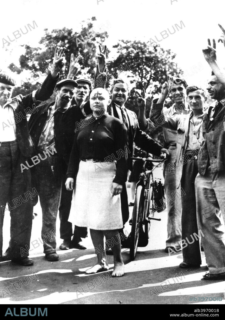 Denunciation and humiliation of a French Nazi collaborator, Paris 1944. The woman has had her head shaved and has a swastika painted on her forehead. The men surrounding her make victory gestures in celebration of the end of Nazi occupation of their city.