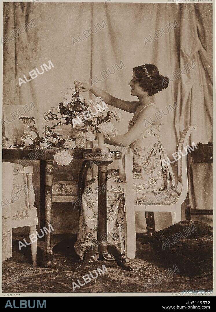 Emile Joachim Constant Puyo, Martin Oldenbourg, Büxenstein & Company, Young Lady with Flowers, paper, heliogravure, image size: height: 22.90 cm; width: 16.60 cm, inscribed: recto: engraved below and above the image: top left: Die Kunst der Photographie 1900, top right: Verlag von Martin Oldenbourg, Berlin S. W, lower left: C. Puyo Paris, lower right: Georg Büxenstein & Comp. Berlin hel.; lower right on the cardboard in white ink: C. Puyo, Paris, K. Ph. 00, stamp: verso and right on the cardboard: artistic photography, staged photography, woman, fashion, clothing, cut flowers, bouquet, containers, interior, sitting figure, profile (side view), arm positions, gestures, furniture and household effects, pictorialism, heliogravure from the magazine Die Kunst in der Photographie, Berlin 1900.