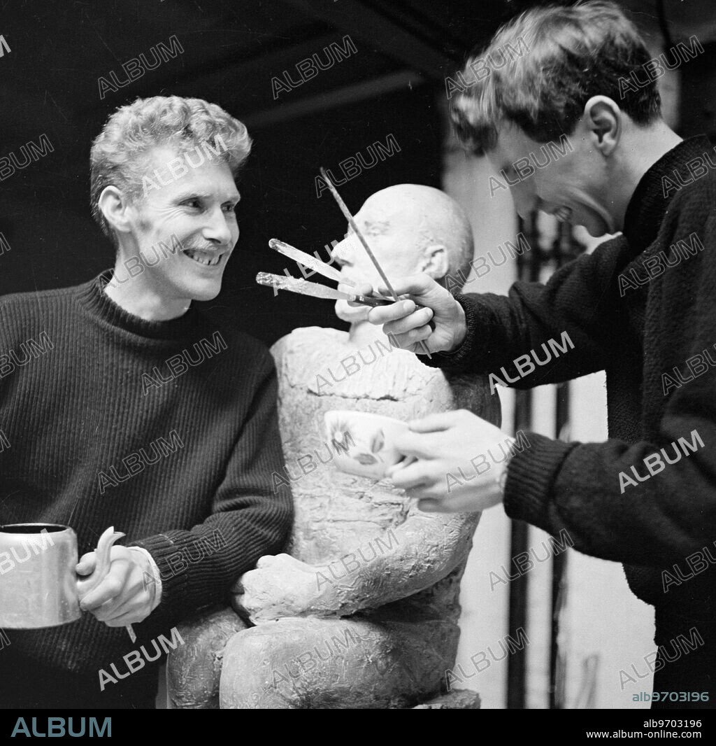 Original 1950s caption. Art in the garage . by Frank Monaco. Derrick Greaves , 27 , is a painter , George Fullard , 31 is a sculptor . Both come from Sheffield , in the North of England . Both , after winning scholarship to Italy and wishing they could have stayed there , have ended by living in London , centre of the English arts , and pooling their sometimes slender resources to hire a large studio behind a garage off the Fulham Road . They are both busy preparing for one-man exhibitions ( ' if ' , as George puts it , we can find one man reckless enough to let us have one ' ) . This is a job needing a long- term patience , and subject to fits of self - criticism and depression , which the average citizen happily does not have to possess or endure . PICTURE SHOWS: ...When Greaves makes critical crack , Fullard replies : ' anyone who tells you sculpture isn't bloody hard work , is a painter ' . Both Greaves and Fullard come from Sheffield , in the North of England . November 1954. Copy of original interview with both artists is held on file at TopFoto.