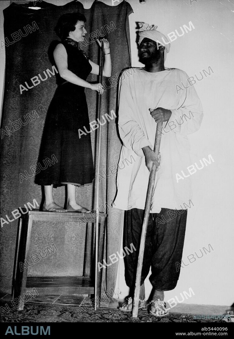 "Baluchistan Giant" - 8½-Feet Tall -- Known in Tehran as the "Baluchistan Giant" Poolud Kurd, 32, demonstrates his extraordinary height to Emy Lou Steiner of Lancaster, Ohio, U.S.A., A U.S. embassy worker in the Iranian Capital. Kurd, a native of Baluchistan, came to Tehran for treatment of a broken back, which prevents him from standing upright. Doctors say but for this ailment he would be at least eight and one half feet tall. July 15, 1950. (Photo by Associated Press Photo).