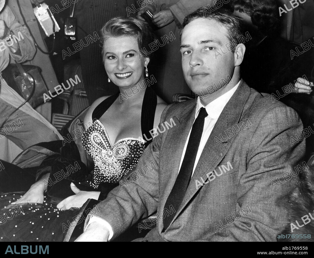 Sophia Loren with Marlon Brando at the Pasinetti Prize ceremony. The Italian actress Sophia Loren sitting next to Marlon Brando. For his performance in the film, the American actor has just received the Pasinetti prize by the journalists union. Rome, 1954.