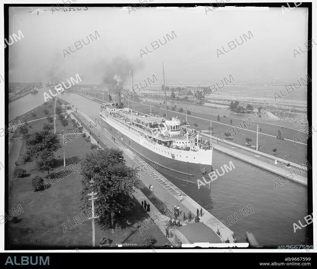 The Locks, Saulte [sic] Ste. Marie, Mich., between 1900 and 1907. The 'Tionesta' passenger ship navigating the Soo Locks at Sault Ste. Marie on the St. Marys River. The 'Tionesta' belonged to the Anchor Line of the Pennsylvania Railroad, and was built between 1900 and 1905. She made a nine-day circuit of the Great Lakes. Thes Soo Locks enabled ships to travel between Lake Superior and the lower Great Lakes. In the distance on the right is the International Railroad Bridge.