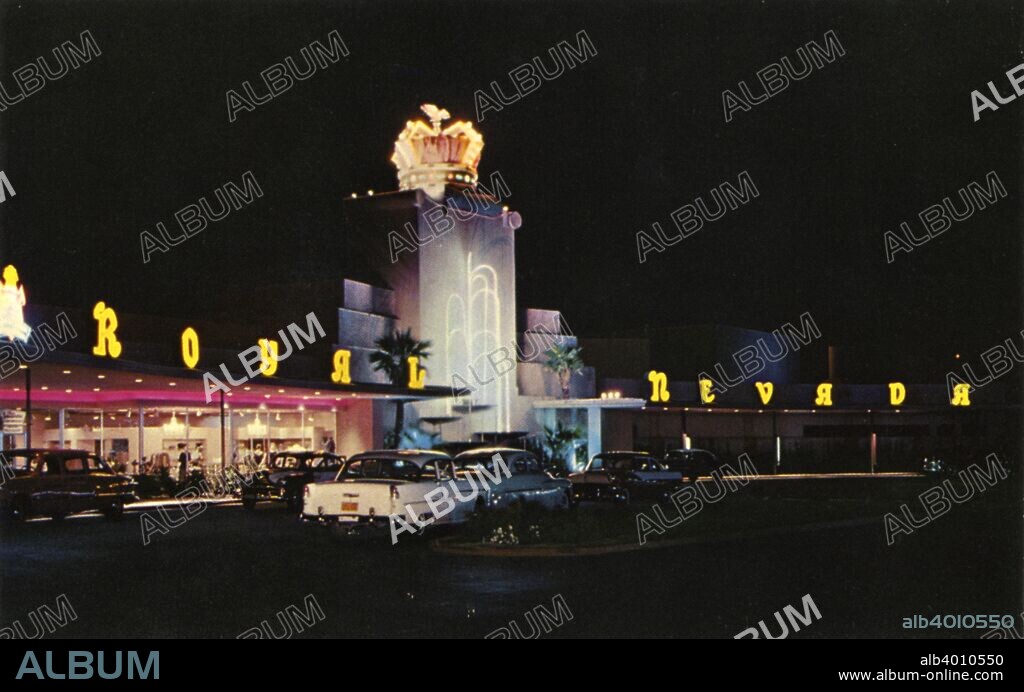 Royal Nevada Hotel, Las Vegas, Nevada, USA, 1956. Vintage postcard showing the entrance of the Royal Nevada Hotel at night. A lighted crown sits atop a tower structure and Royal Nevada is spelled out in neon on the rooftop. Cars are parked at the entrance.