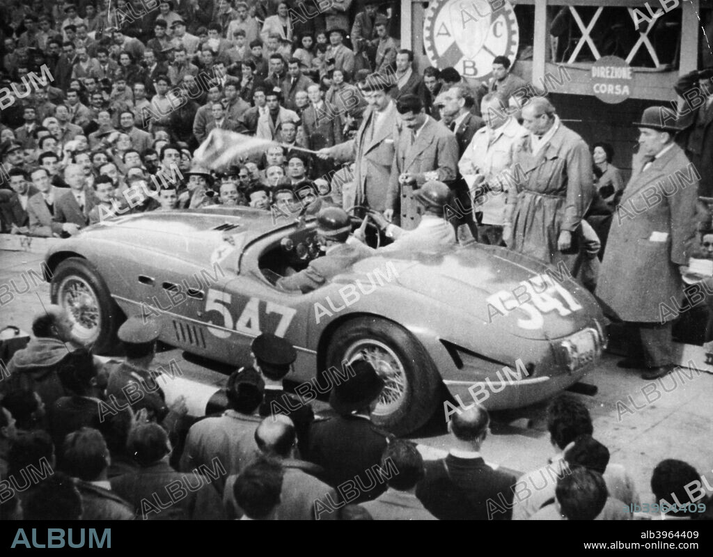 G Marzotto in a 4.1 Ferrari, taking part in the Mille Miglia, 1953. They are at the start of the race, with an official by the side of them starting the stopwatch. His co-driver is Marco Crosara. They were the eventual winners of this race. Marzotto had also won the Mille Miglia in 1950.