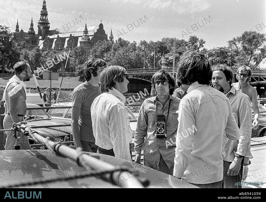 STOCKHOLM 1970-06-15.. Lee Hazlewood (i mitten), amerikansk sångare, kompositör och skivproducent, som tillsammans med Torbjörn Axelman och Lasse Åberg gör TV/album-produktionen Cowboy in Sweden. I bakgrunden ses Nordiska museet.. Foto: Bo-Aje Mellin / RiR / SVT / Kod: 5600. Notis publ. i RiR 28/70 sid. 2.. RiR 19877 sv/v neg  . Kameror.