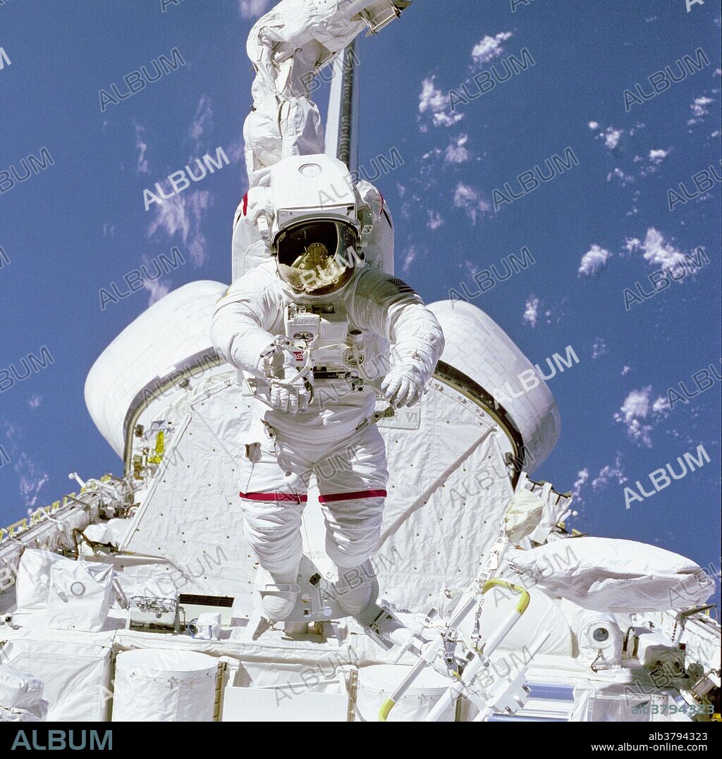Astronaut Bruce McCandless II, STS-41B mission specialist, tests a Mobile Foot Restraint (MFR) attached to the Remote Manipulator System (RMS) aboard the Space Shuttle Challenger. McCandless appears to be walking on cargo, but is realy being flown over it by the combination MFR and RMS. His helmet visor reflects parts of the payload bay that can't be seen in the larger portion of the photo. Behind him can be seen both the Orbital Maneuvering System (OMS) pods.