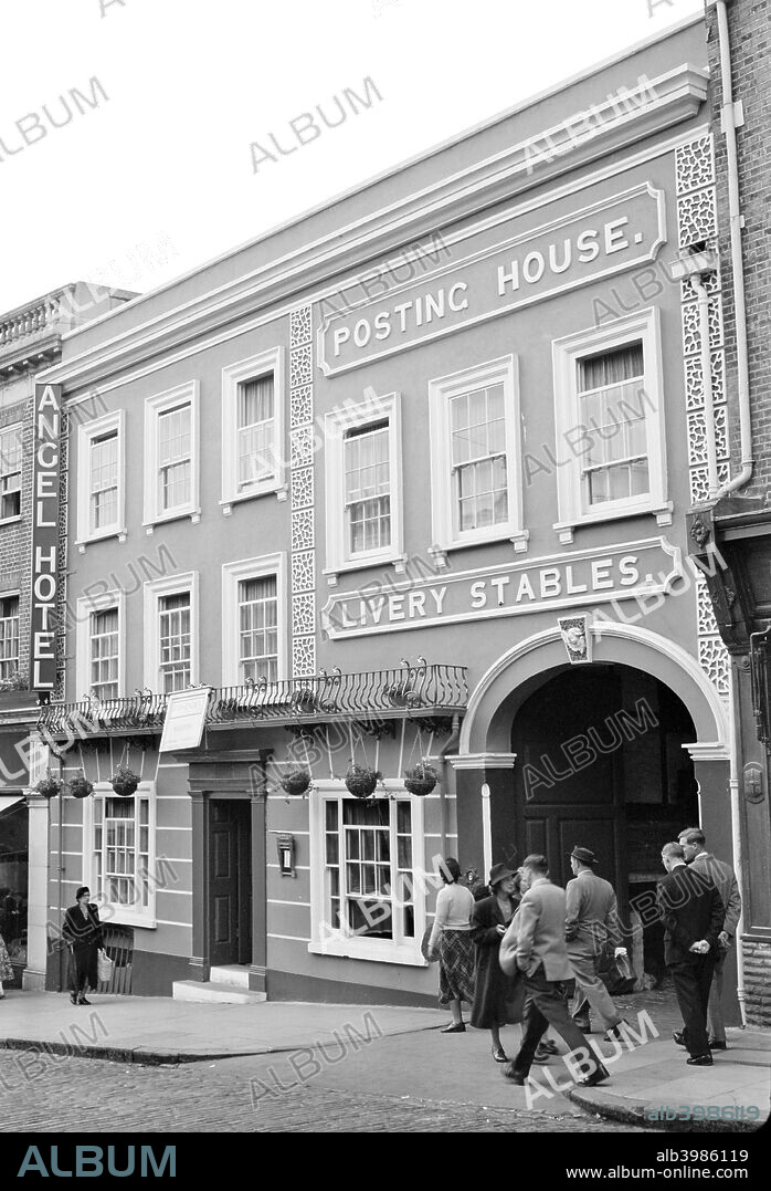 The Angel Hotel, High Street, Guildford, Surrey, 1951. Three medieval timber framed buildings were adapted to make this coaching inn. A 13th-century undercroft shows that one of these was originally a shop. The inn was created in the 16th century and a new frontage was built in the 18th.