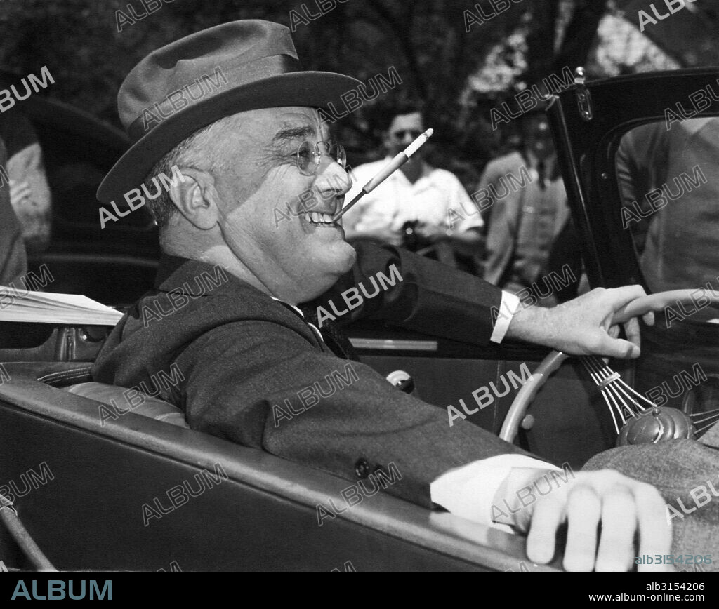 Warm Springs, Georgia:  1939. With a cigarette in a holder clenched in his teeth, a smiling Franklin Delano Roosevelt sits jauntily at the wheel of his convertible.