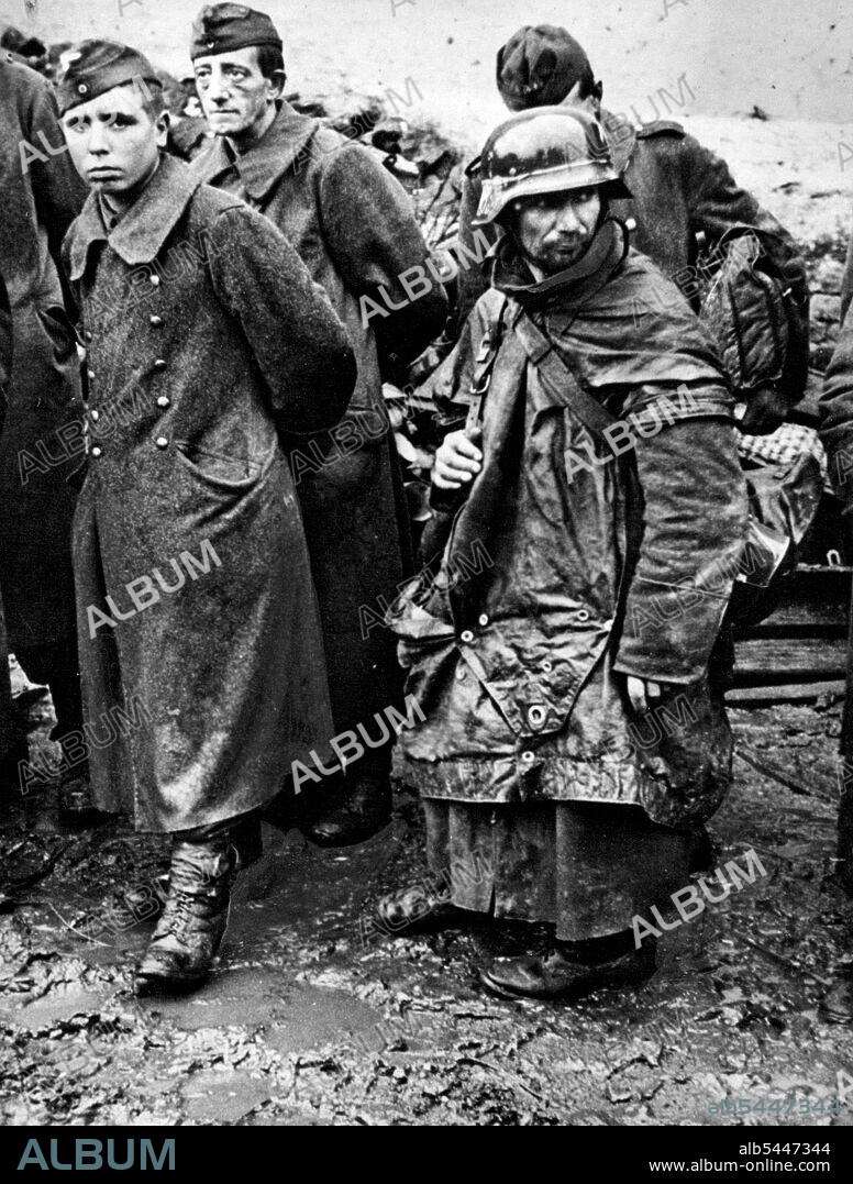 Nazi Driven From Hurtgen Forest : Battle-weary, surrendered Germans stand in the mud of captured Reich soil as they wait near Jungersdorf to be processed for internment. These Naziz were among the last enemy troops to surrender to First U.S. Army soldiers at the close of the battle for the Hurtgen Forest. December 12, 1944, American troops broke through the forest and reached the Roer River in three places, driving to a point within a mile and a quarter of Duren, river bastion on the road to the industrial center of Cologne. January 19, 1945. (Photo by U.S. Office of War Information Picture).