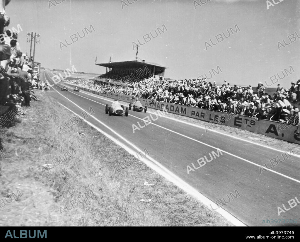 Marne Grand Prix, Rheims, France, 1952. Louis Rosier, in the Ferrari, leads Jean Behra, in a Gordini as they pass a grandstand. Behra eventually emerged victorious, with Rosier finishing in fifth place.