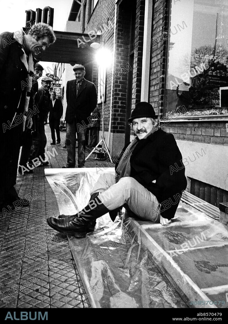 Hans Hasse Alfredson Skådespelare revyartist författare filmregissör 1971. I samband med premiären av filmen Äppelkriget sätter Hasse Alfredson sitt stjärtavtryck i cementen utanför premiärbiografen i Tomelilla. Tage Danielsson tittar på. (c) Sydsvenskan / IBL.
