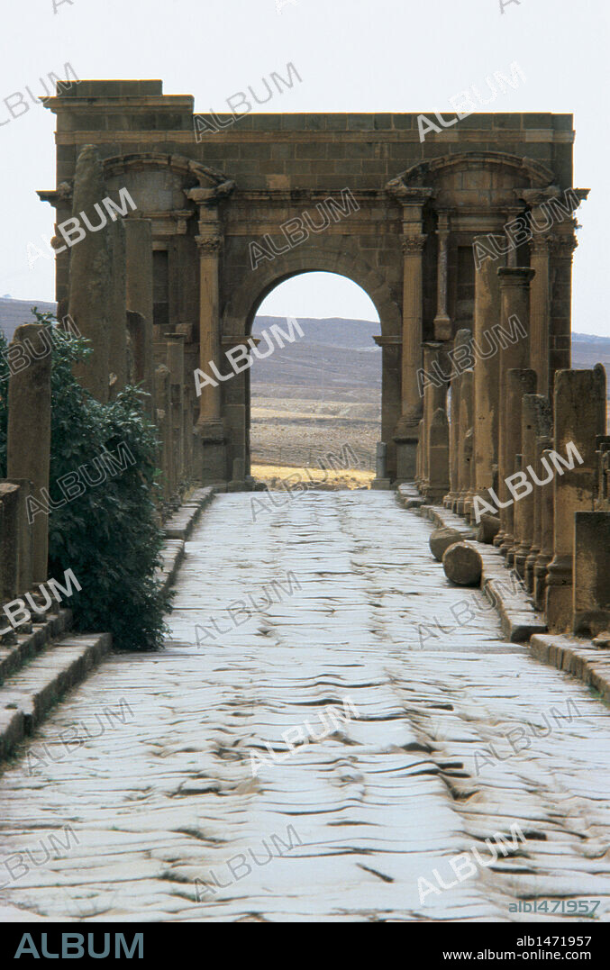 ARTE ROMANO. NORTE DE AFRICA. Calzada romana. Al fondo, el ARCO DE TRAJANO. Timgad. Argelia.
