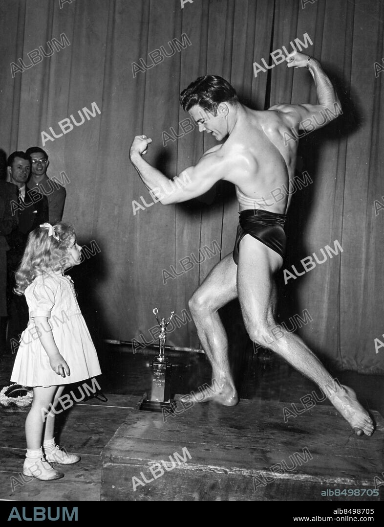 Orig. bildtext... LITTLE MISS, AND BIG MR. WASHINGTON. Make me a muscle, would seem to be the cry of Darlene Smith, 3-year-old daughter of weight-lifter Lt. Dick Smith. The object of her admiration is 23-year-old Irving Bridgers, who was chosen Mr. Washington, 1948 at the 8th annual weight lifting championships held in the nation's capital. Anm. Curious Moments s.88 Bildarkivets katalog nr40.6 Styrka Muskler Beundran Posering Kroppbyggare Jämförelser sites: WASHINGTON DC ;USA.