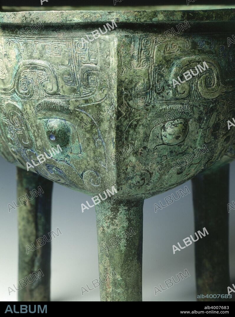 A ritual bronze cauldron (ding) with upright loop handles supported on three plain cylindrical legs. The three lobes are each cast with a large and elaborate taotie mask, whose two large hooked horns flank a crest rising from its ridged nose, the jaws have tight hooks, the eyebrows are hatched and the eyes are in higher relief. A ding is a ritual vessel for cooked food with a round body and three legs.  The shape was made and used throughout Shang-Han dynasties.  Ritual vessls were used to offer food to ancestors.