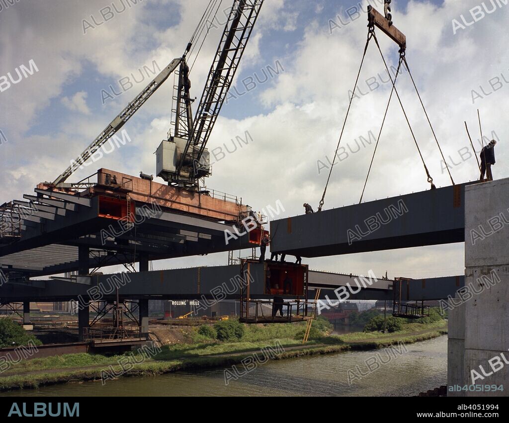Tinsley Viaduct under construction, Meadowhall, near Sheffield, South Yorkshire, 1967. The Tinsley Viaduct is one of the major structures on the M1. It forms a giant interchange with access to and exits from the M1 situated at each end. Originally designed on the back of a cigarette packet at a dinner dance, the viaduct cost £6 million to build and has a length of 1088 metres. It crosses the Sheffield Canal and the Midland Mainline railway. In the photograph, one of the steel box sections can be seen being lifted into place.