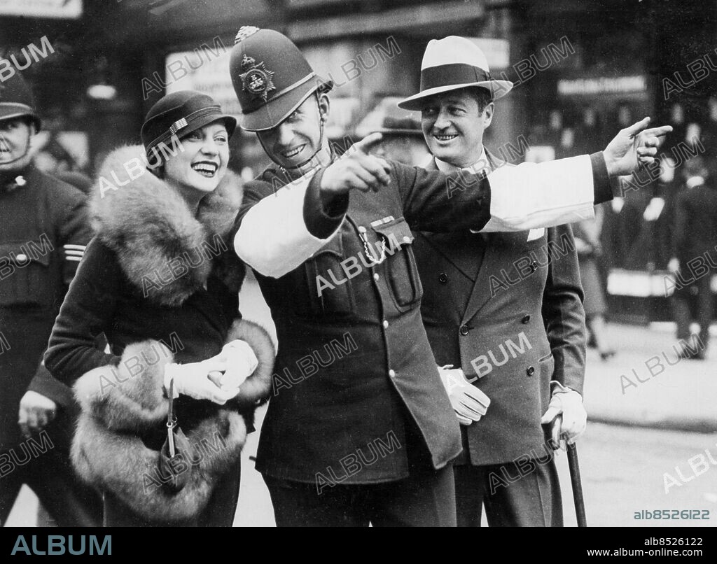 Orig. bildtext... THE BEST-DRESSED FILM STAR IN LONDON. Miss Lilyan Tashman, the famous film star who has been described as the best-dressed star in Hollywood, has arrived in London with her husband, Mr. Edmund Lowe, one of the screen's most brilliant and versatile actors. Mr. Lowe who is world famous for his film partnership with Mr. Victor McLaglen, claims to be the originator of the catch-phrase of Sez-You which is universally known. Miss Lilyan Tashman, is a s famous on the stage as the screen, and has starred in many successful Broadway shows. O.P.S. Miss Lilyan Tashman photographed with her husband, Mr. Edmund Lowe asking their way of a London policeman during a tour of the City today. Anm. L Tashman, 1899-1934, amerikansk skådespelare, stumfilmsstjärna Visar vägen Peka Leende Pälskragar Trafikpoliser Trio CD413 persons: EDMUND LOWE;LILYAN TASHMAN sites: USA*;LONDON;STORBRITANNIEN.