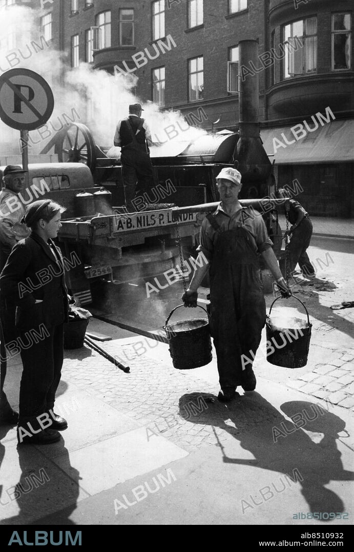 Asfaltläggare asfaltkokare asfaltarbetare asfalterare med ok spannar på gata i Malmö 1953.. Foto: Ernst Henriksson / Sydsvenskan / IBL Bildbyrå.