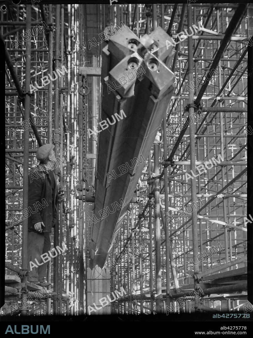 JOHN LAING. Construction of Coventry Cathedral, West Midlands, 1960. A man standing on scaffolding watching a nave column being hoisted into position during the construction of the cathedral.