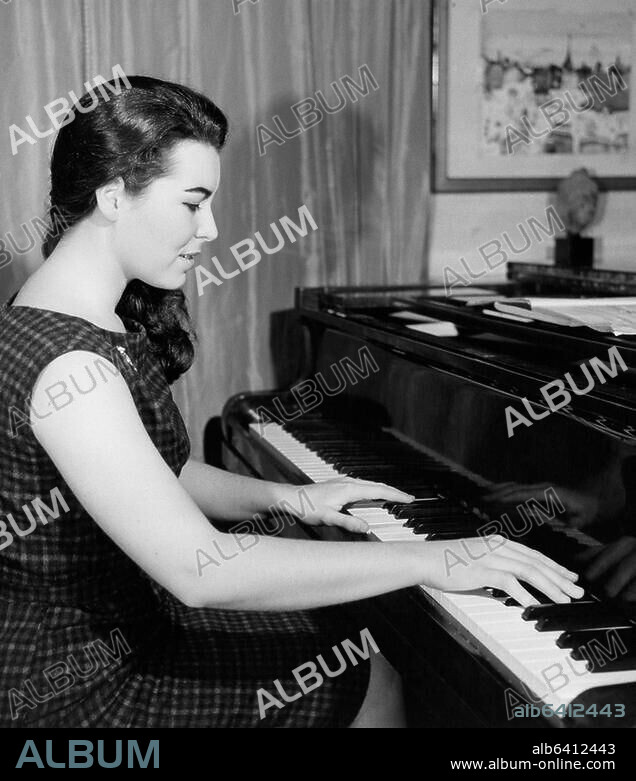 LOUIS INGIGLIARDI. Mercier, Sylvie; French pianist and painter (since 1987 she has been signing her works with her mother's name "de Flandre").-Sylvie Mercier at the grand piano in her apartment in Paris.-Photo, October 1961. Vintage print, 19.5 x 24.5cm.