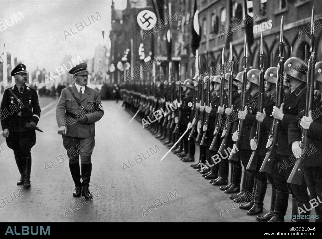 Adolf Hitler reviewing Leibstandarte troops at the Nuremberg Rally, Germany, 1935. Hitler (1889-1945) inspecting soldiers of the Leibstandarte SS Adolf Hitler, his personal bodyguard regiment. He is accompanied by Reichsführer Heinrich Himmler (1900-1945), head of the SS. A print from Adolf Hitler. Bilder aus dem Leben des Führers, Hamburg: Cigaretten/Bilderdienst Hamburg/Bahrenfeld, 1936.